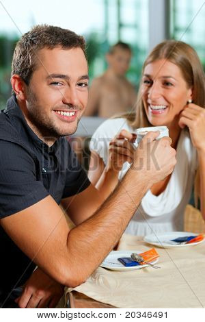 Jong koppel - man en vrouw - drinken koffie in een café voor een glazen gevel