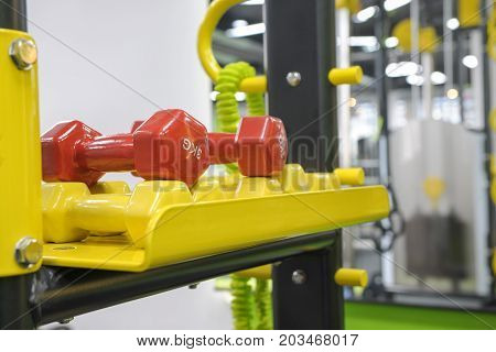 red and yellow sports dumbbells and kettlebells on stand closeup