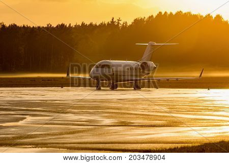 Plane parking at the airport during a foggy sunrise. Modern jet aicraft. Golden time.
