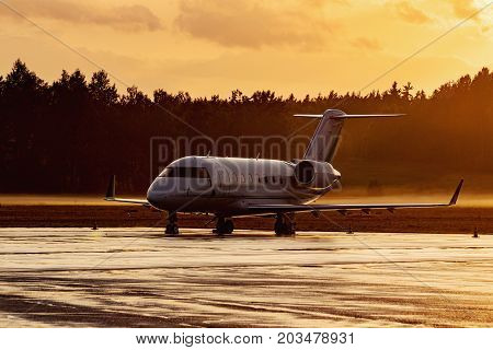 Plane parking at the airport during a foggy sunrise. Modern jet aicraft. Golden time evening.
