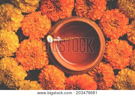 flower rangoli for Diwali or pongal or onam made using marigold or zendu flowers and red rose petals over white background with diwali diya in the middle, selective focus
