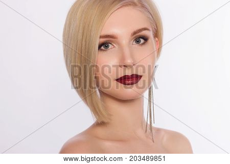 The lovely blonde with evening cosmetics on a face. Lips in style to an ombra and shooters in the eyes. Jewelry earrings. Cosmetology beauty shop fashion