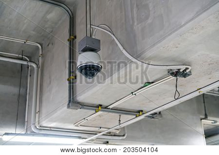 CCTV security camera installed on ceiling building. Dome outdoor cam for parking area.