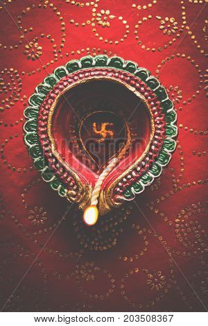 stock photo of beautiful diwali diya, isolated over decorative background, moody lighting and selective focus