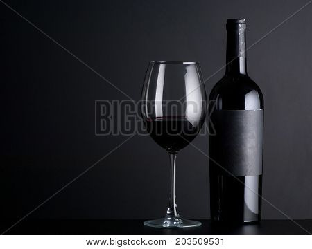 bottle red of wine with a glass on a black background
