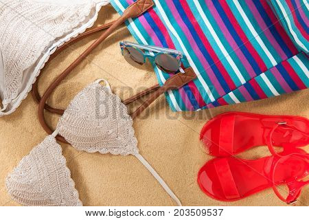 set of bright summer clothes for the beach on the golden sand