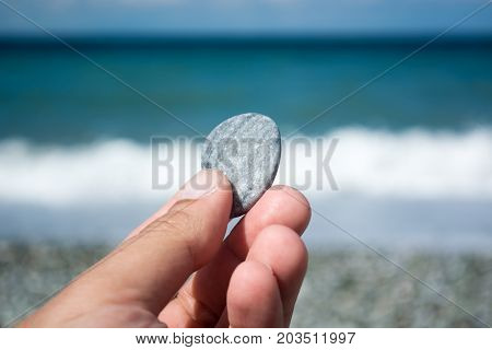 Hand With Small Stone On The Beach