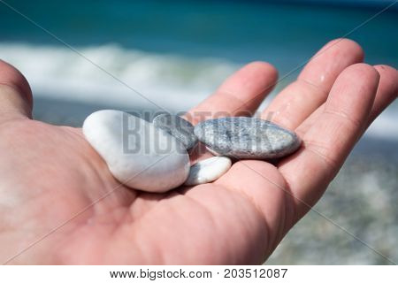 Hand With Small Stones On The Beach