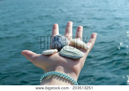 Girl Hand Full With Small Stones On The Beach