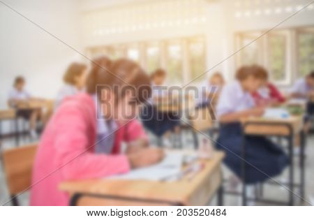 Blurred of Asian School students in uniform taking examination and writing answer sheet in classroom educational school view of having exams in class on seat rows Education system tests of Thailand