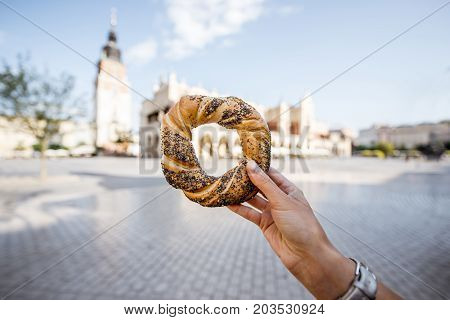 Holding prezel, traditional polish snack on the Market square in Krakow