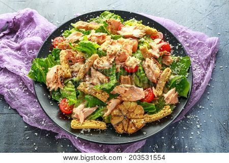 Cesar salad with salmon, cherry tomatoes, garlic, crutons, romaine lettuce and parmesan
