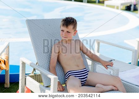 Young Boy In A Swimsuit On A Shelf By The Pool