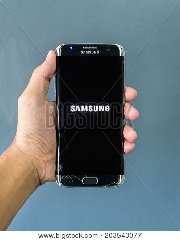Chiangrai Thailand: September 2 2017 - Human hand holding broken Samsung Galaxy S7 edge smartphone and showing logo 'SAMSUNG' on screen