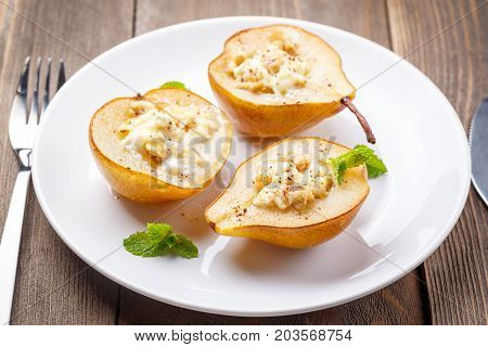Pears baked with Ricotta cheese nuts honey and cinnamon on rustic wooden background