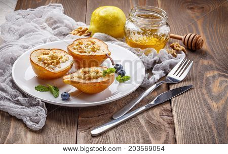 Pears baked with Ricotta cheese nuts honey and cinnamon on rustic wooden background