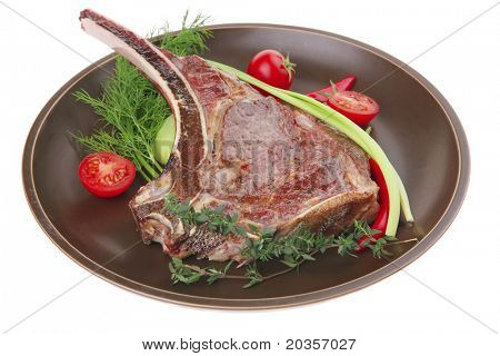 cibo di carne: arrosto nervatura sul piatto scuro con timo pepe e pomodoro isolato su sfondo bianco