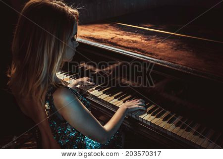 Beautiful woman with fancy elegant dress posing in the piano room