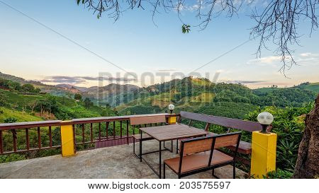Table and chairs on the terrace for dining and enjoy the beautiful natural landscape of forest and mountains in the morning atmosphere at Doi Mae Salong view point in Chiang Rai Province Thailand