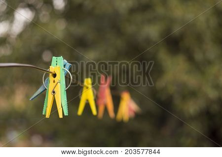 colored clothespins hanging on a rope with blurred background