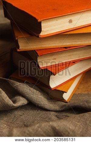 A Stack Of Paper Books In Orange Color On Textured Wooden Surface. Autumn Mood Concept. Time To Read