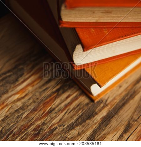 A Stack Of Paper Books In Orange Color On Textured Wooden Surface. Autumn Mood Concept. Time To Read
