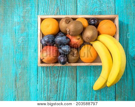 Wooden box of healthy fresh fruit on blue wooden background. Top view.