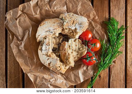 Slices Of Wholegrain Brioches Made With Coriander Seeds And Tomatoes, Served On Paper And Wooden Tra