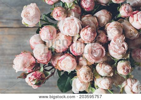 Pink shrub roses bouquet on wooden background. Beautiful wedding shabby chic bouquet of flowers. Closeup view. Vintage toning