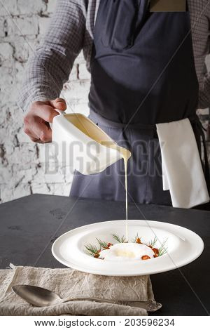 Waiter pouring broth to mushroom cream soup. Original restaurant serving of delicacy meal, copy space