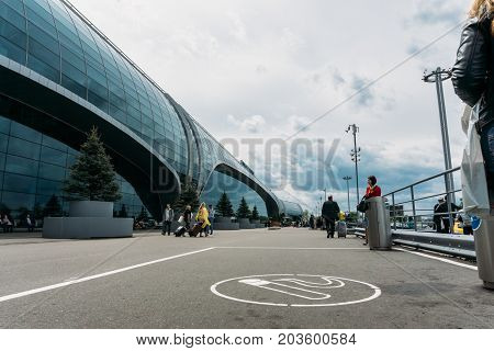 Moscow, Domodedovo, Russia - May 29, 2017: Place for smoking or smoking area with smoking people in front of the main entrance to Domodedovo airport