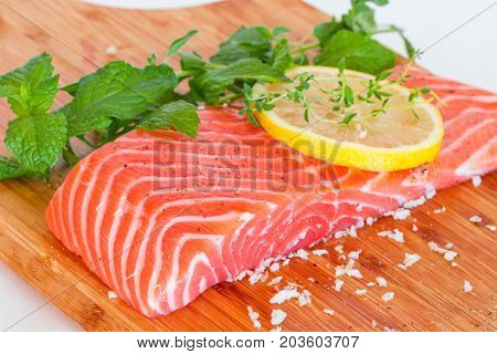 fresh raw salmon on wooden cutting board with seasonings