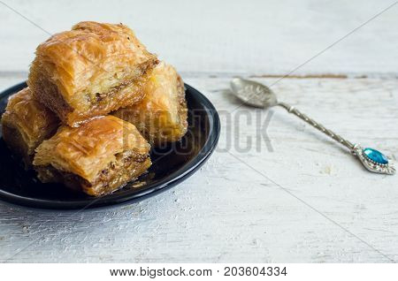 Turkish national delight baklava with pistachios walnuts and honey on a white wooden background. Traditional eastern dessert.