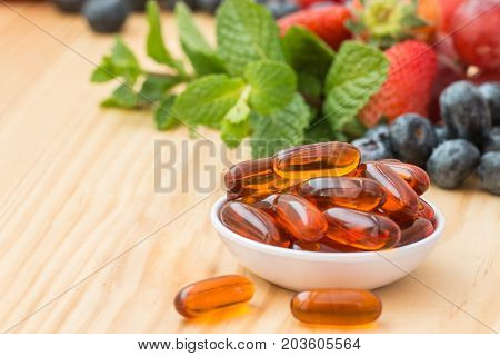 Lecithin gel vitamin supplement capsules on wooden table.