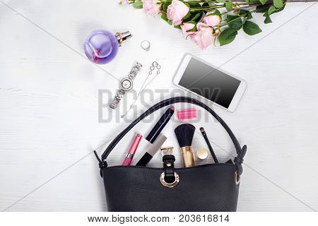 Flowers perfume watch bracelet mobile phone handbag cosmetics on a white wooden background