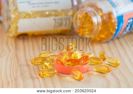 Fish Oil Omega 3 With Vitamin D Capsules Good For Heart Health On Wooden Table And In Bottle.