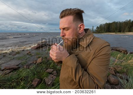 Bearded Man with a cigarette on the seashore in stormy weather