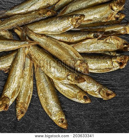 lots of fresh smoked sprats on dark stone slab