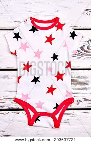 Baby high quality soft bodysuit. Newborn baby white stars print romper on old wooden background.