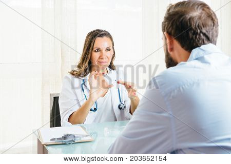Female doctor removes the lid of a pressurized cartridge inhaler to a male patient at her office