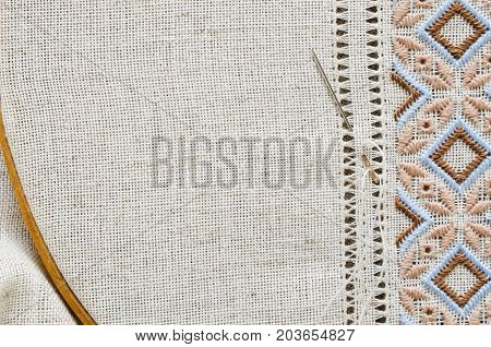 Embroidered fragment on flax by brown and beige cotton threads. Embroidery texture flat stitch. Ukrainian ethnic ornament. Hemstitch.