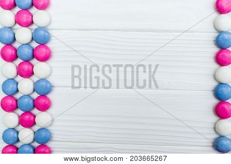 Frame from colorful mint coated candies texture on white wooden background. Top view. Copy space