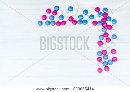 Frame from colorful mint coated candies texture on white wooden background. Top view. Copy space