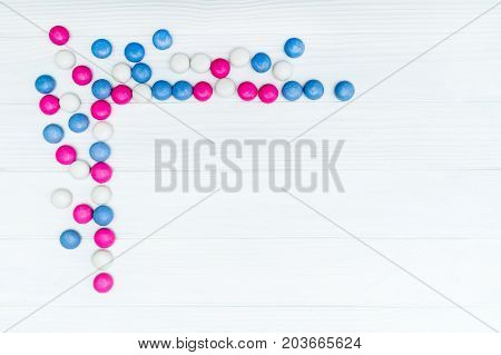 Frame from colorful mint coated candies texture on white wooden background. Top view. Copy space