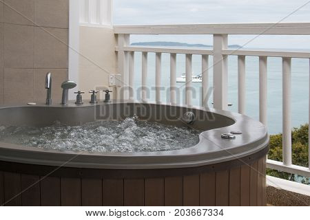 Wooden bathtub with swirling water at balcony.