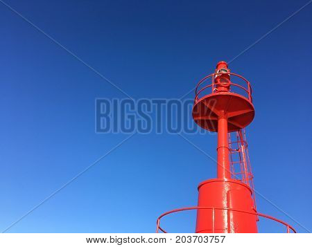 Red Lighthouse at port with blue sky .