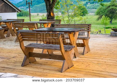 Wooden benches and tables on the terrace in restoane near the lake in the background of the mountains.