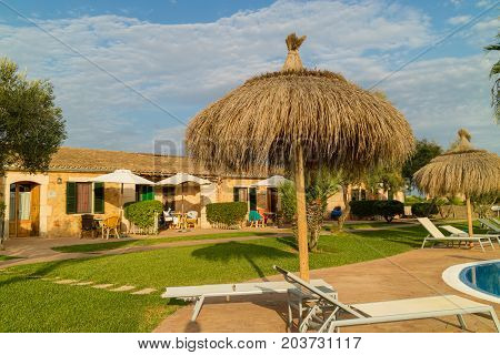 CAMPOS MALLORCA SPAIN - August 30 2017: Panorama of a swimming pool from a Mediterranean finca buildings built in traditional island style and garden with palm trees and orange trees. Balearic islands. Summer 2017.