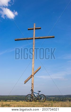 Mountain biking near a large wooden cross on the mountain