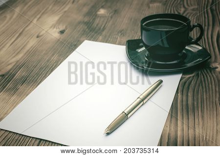 Empty Letter page fountain pen and cup of coffee on the burnt table background. Writter desk table.